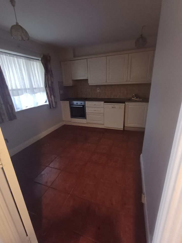 Empty fitted kitchen with tiled floor, every item cleared out and nothing left on the counters
