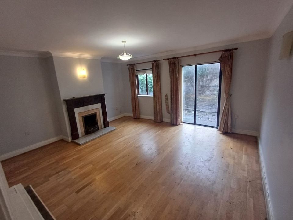 Fully cleared living room, wooden floor, fireplace and patio doors with no furniture remaining