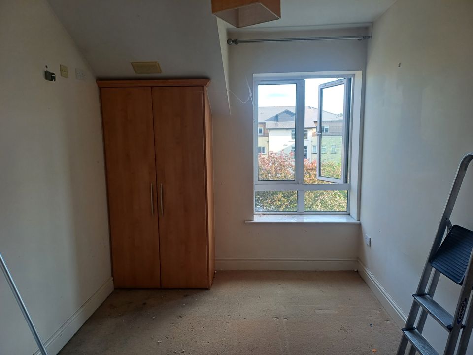 Emptied apartment bedroom, only a wardrobe left, bare walls and window, ready for handover