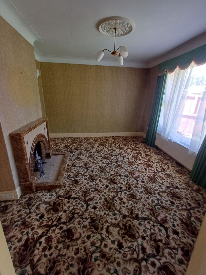 Fully cleared front room: patterned carpet, tiled fireplace and green curtains, nothing left on floor