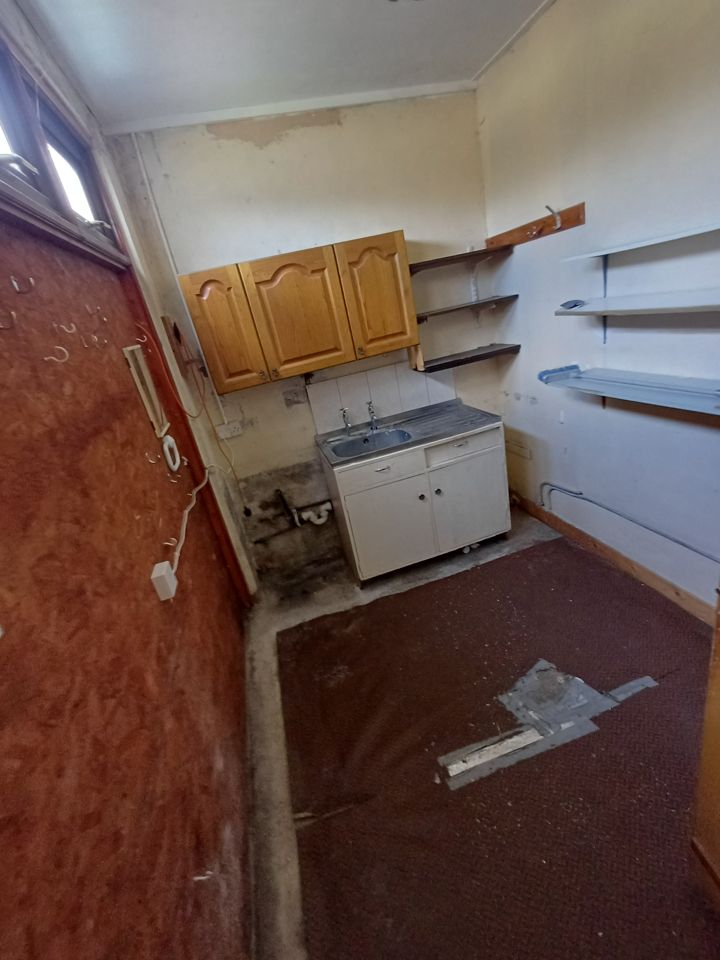 Utility room stripped back: empty shelves, sink unit and bare floor after clearance