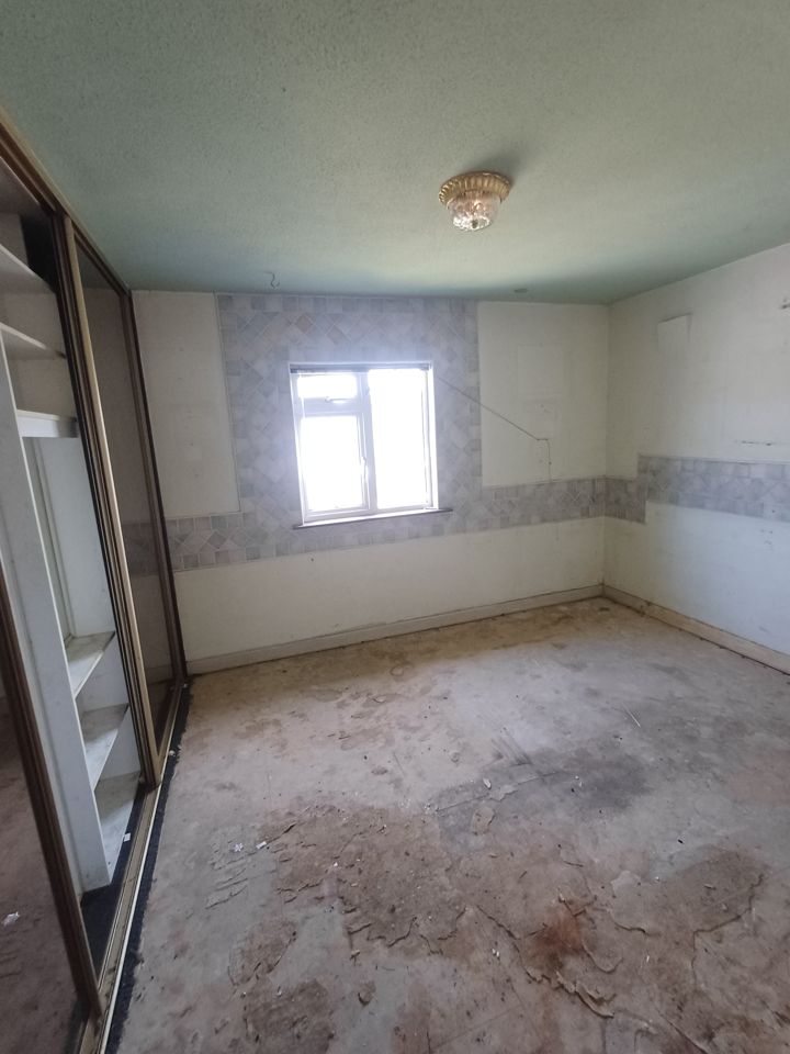 Bedroom stripped completely bare, open sliding wardrobe and bare stained floor after clearance