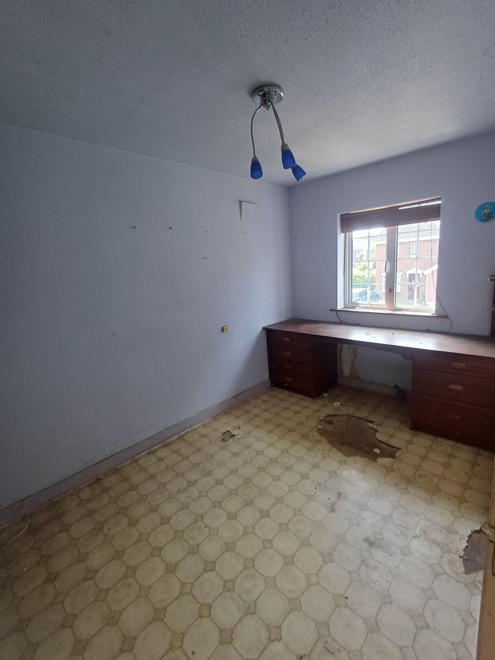 Empty bedroom with built-in desk left behind, vinyl floor cleared, ready for handover