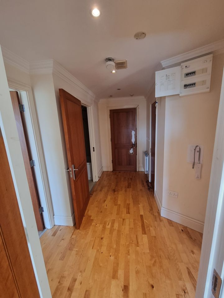 Emptied apartment hallway with wood floor, all contents removed through to the front door