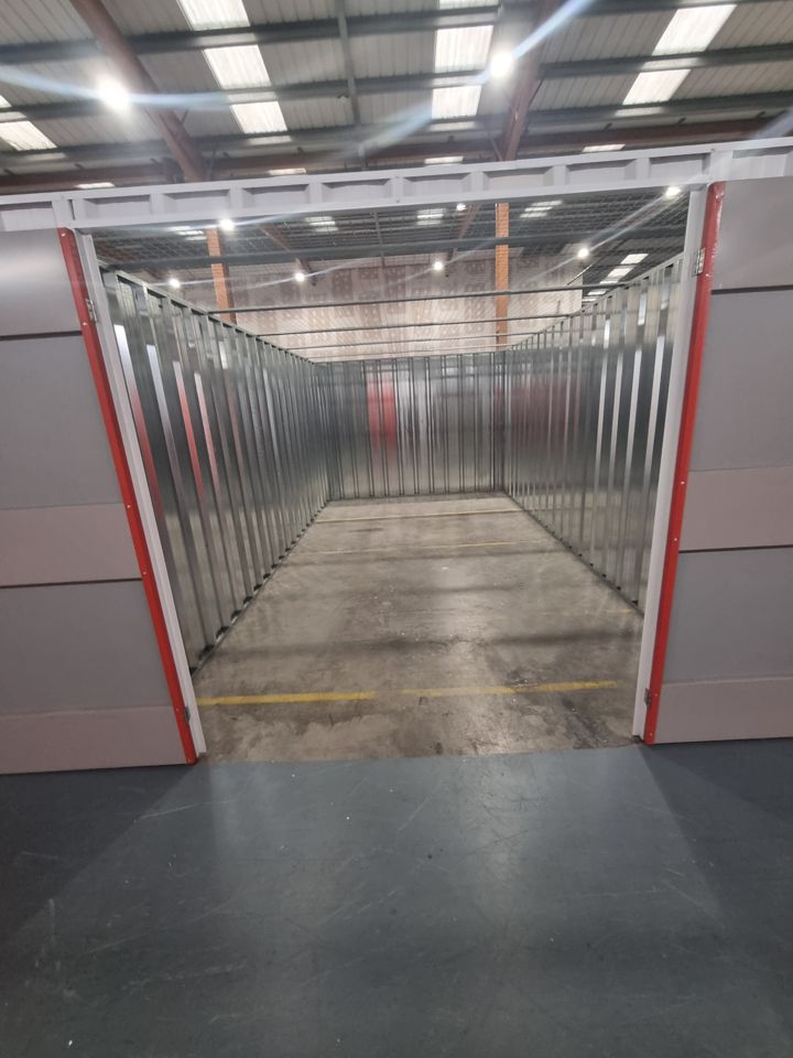 Fully emptied steel-lined self-storage unit with doors open, clean concrete floor ready for handover