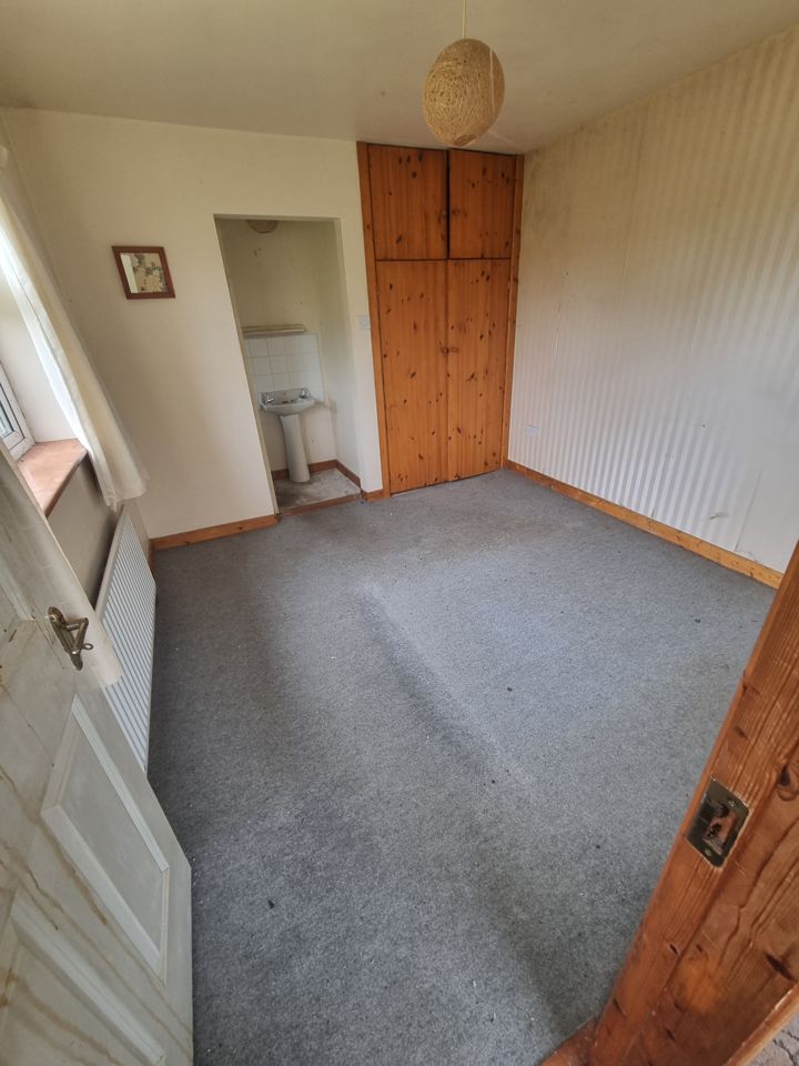 Cleared bedroom with grey carpet, built-in pine wardrobe and washbasin alcove, completely empty