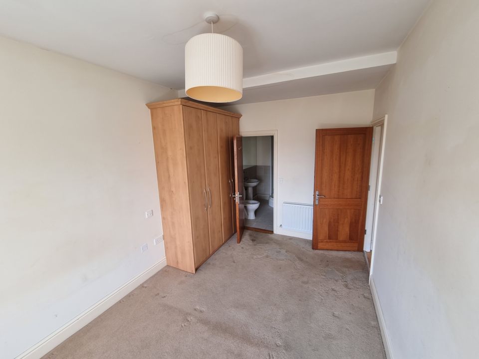 Cleared master bedroom with fitted wardrobe and en-suite door, carpet fully emptied