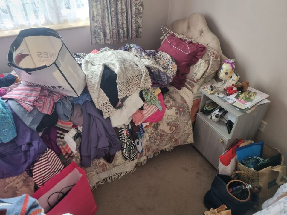 Cluttered bedroom with clothes and furniture before clearance