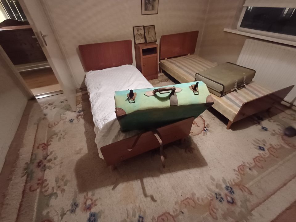 Elderly-style bedroom with twin teak beds, vintage suitcases and floral rug awaiting a full house clearance