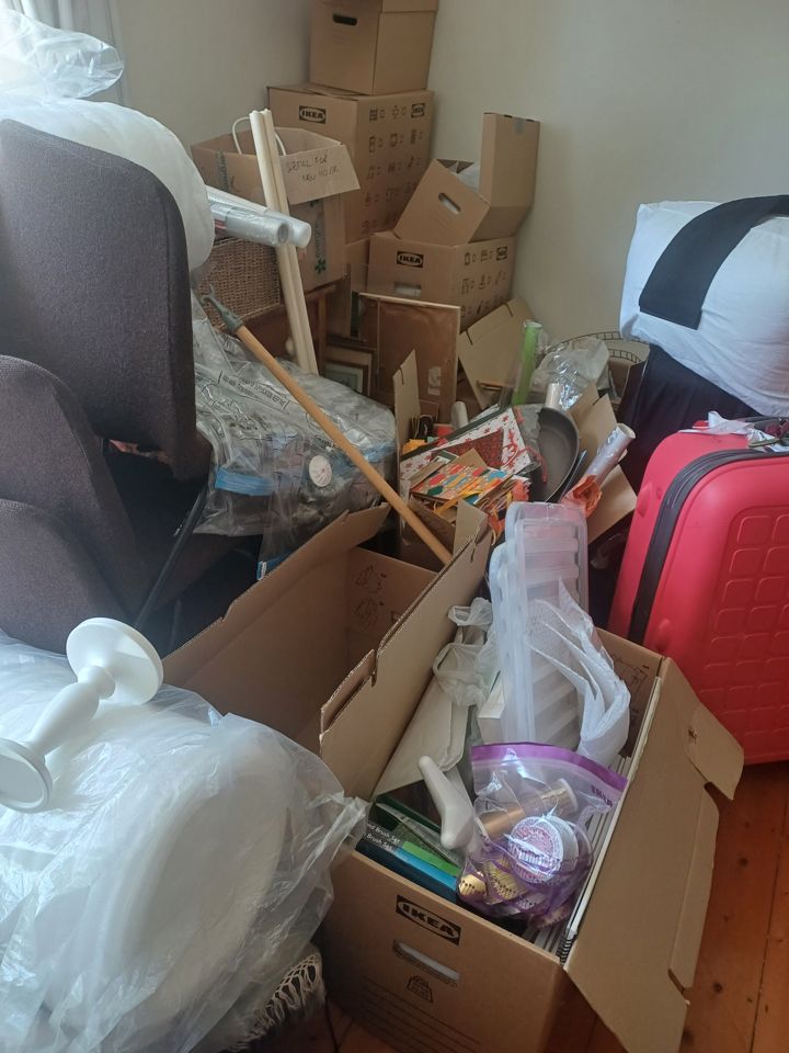 Spare room packed with cardboard boxes, suitcases, bags and stored household items