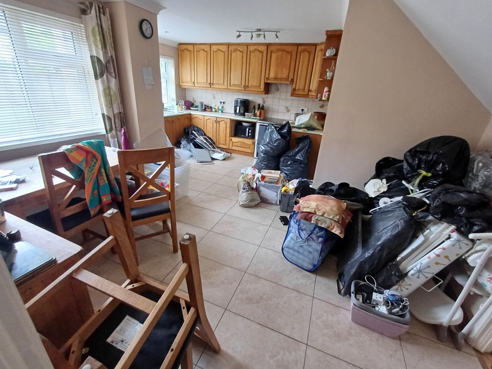 Kitchen-diner floor piled with black bin bags, boxes, laundry and household items awaiting removal