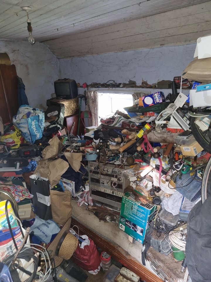 Old cottage room packed wall to wall with electronics, tools, bags and boxes
