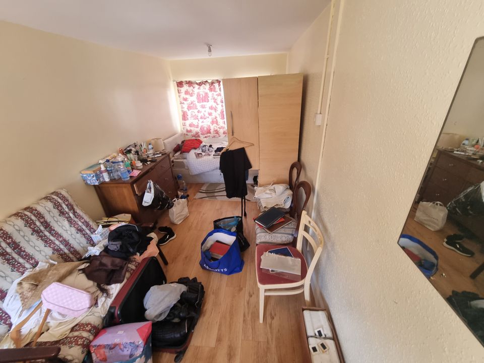 Bedroom strewn with clothes, bags, suitcases and boxes across the floor before clearance