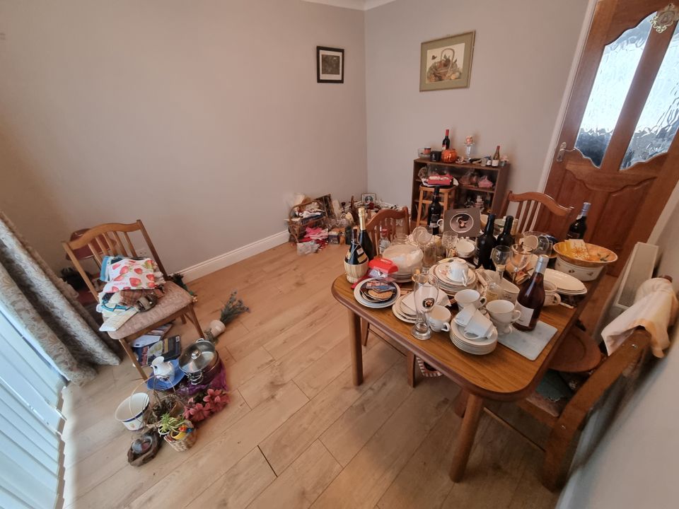 Dining room table stacked with crockery and glassware, household items scattered across the floor