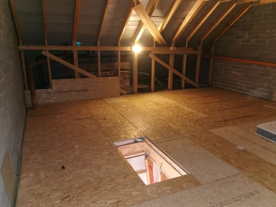Cleared attic with the hatch and boarded floor visible