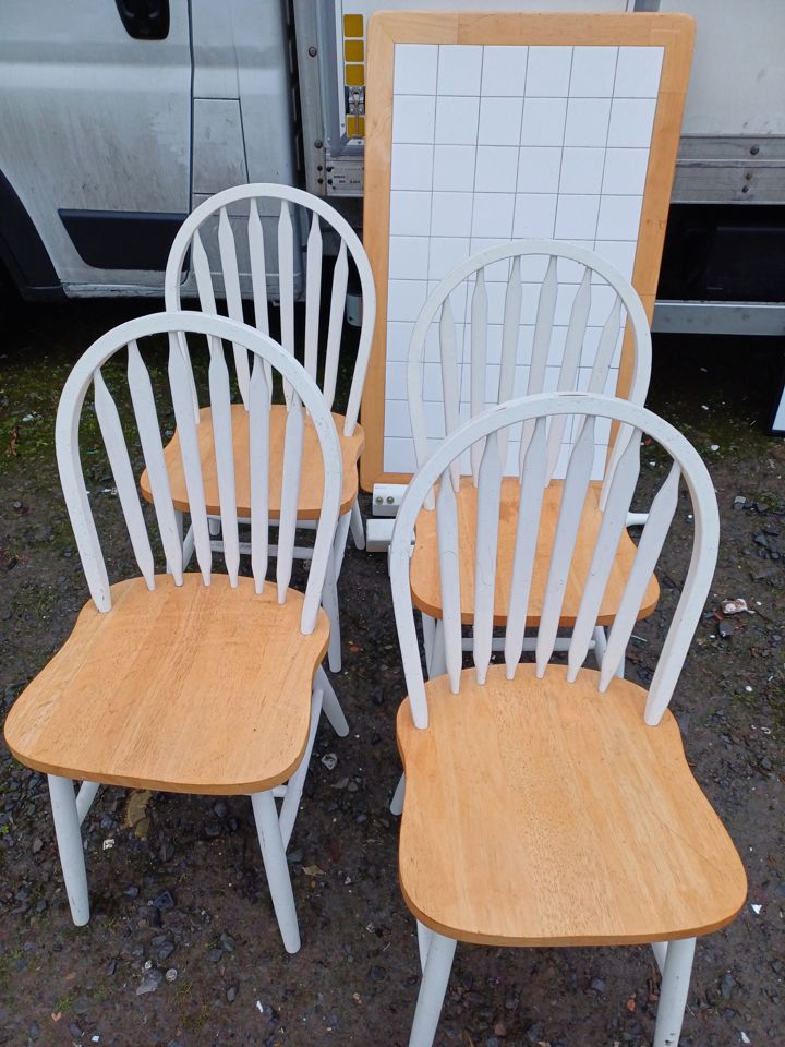 Four wooden kitchen chairs and a tiled table top set out beside the van for removal