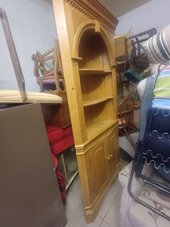 Pine corner cabinet, chairs, loungers and sideboards piled tightly in a tiled room ready for removal