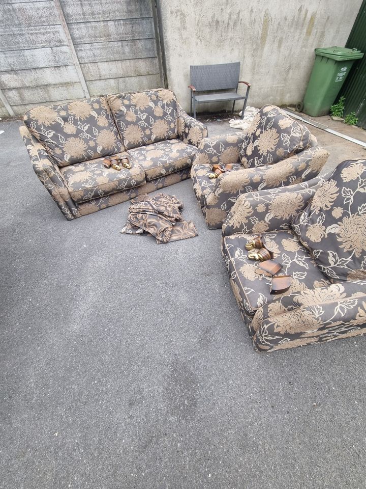 Floral three-piece suite placed outside on tarmac yard awaiting collection and removal