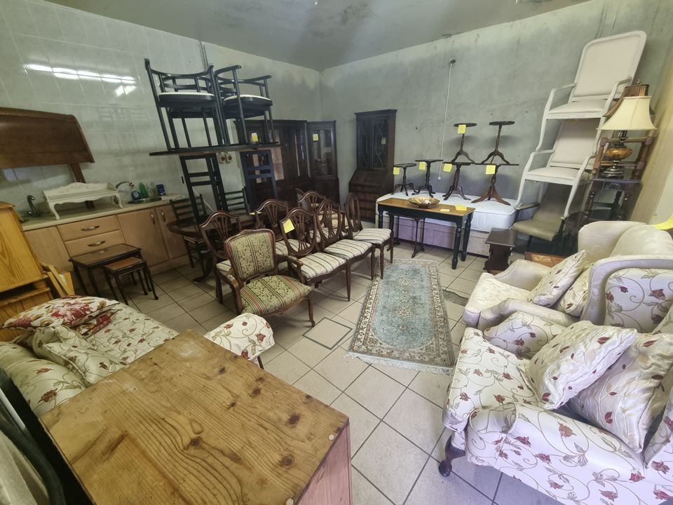 Large room full of furniture: dining chairs, display cabinets, sofas, side tables and stacked bar stools
