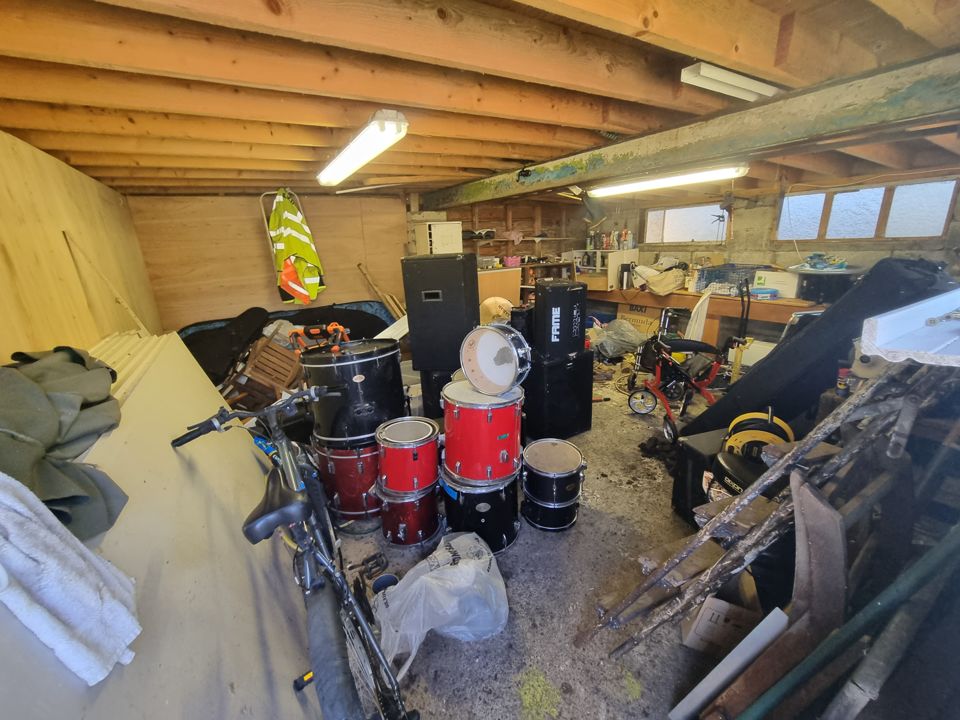 Garage with bikes, a drum kit and stored items before clearance