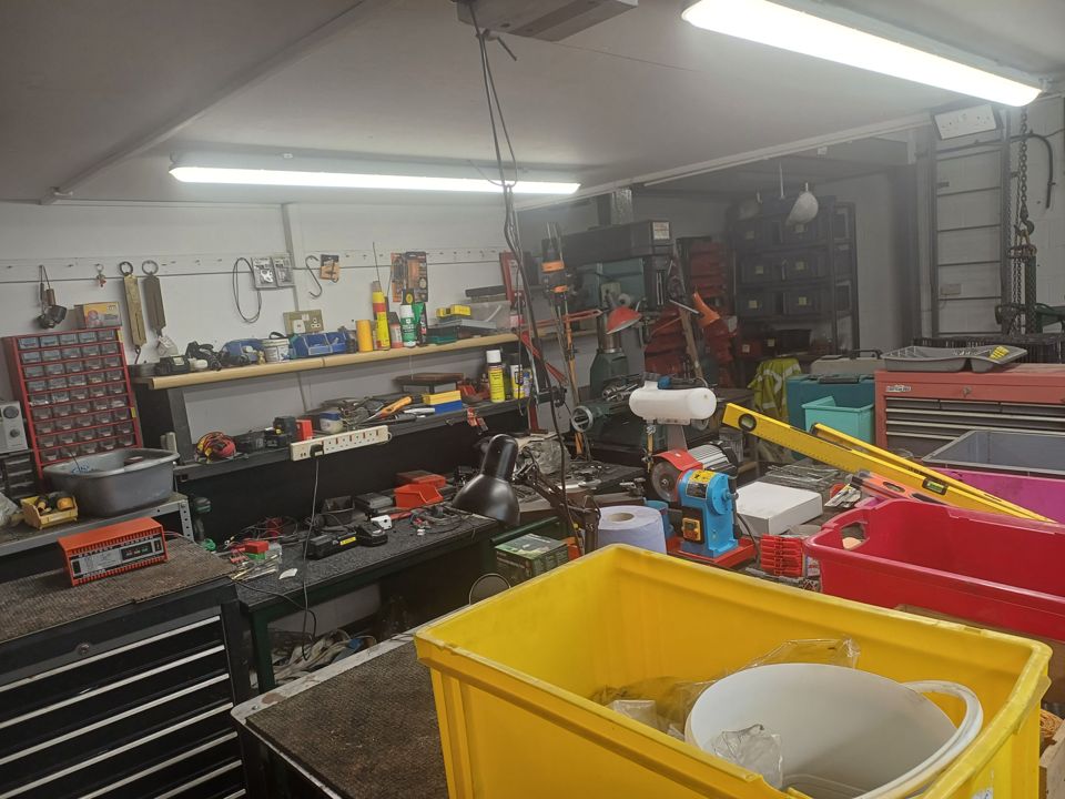Packed home workshop garage: benches, tool chests, crates and clutter covering every surface