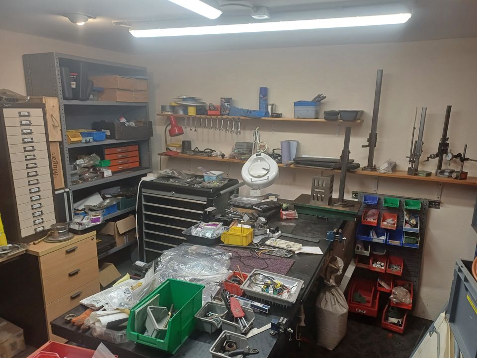 Workshop room with tool chests, parts bins, drawers and a bench covered in clutter
