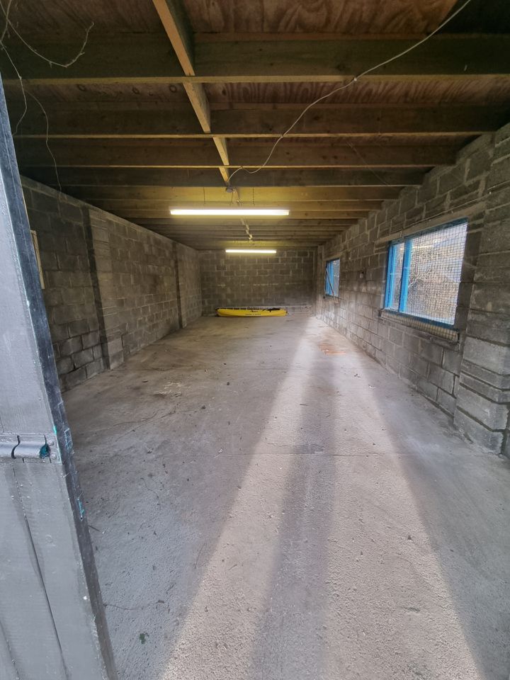 Swept-out block-built garage, empty concrete floor with sunlight through the windows after clearance