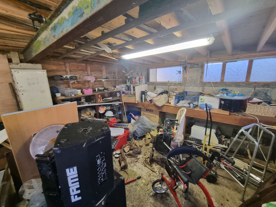 Garage workshop with benches, bikes and boxes before clearance