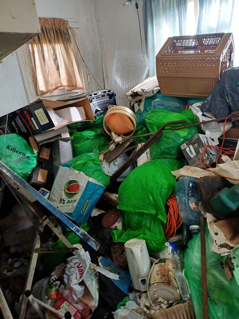 Hoarded room with bags and belongings before clearance