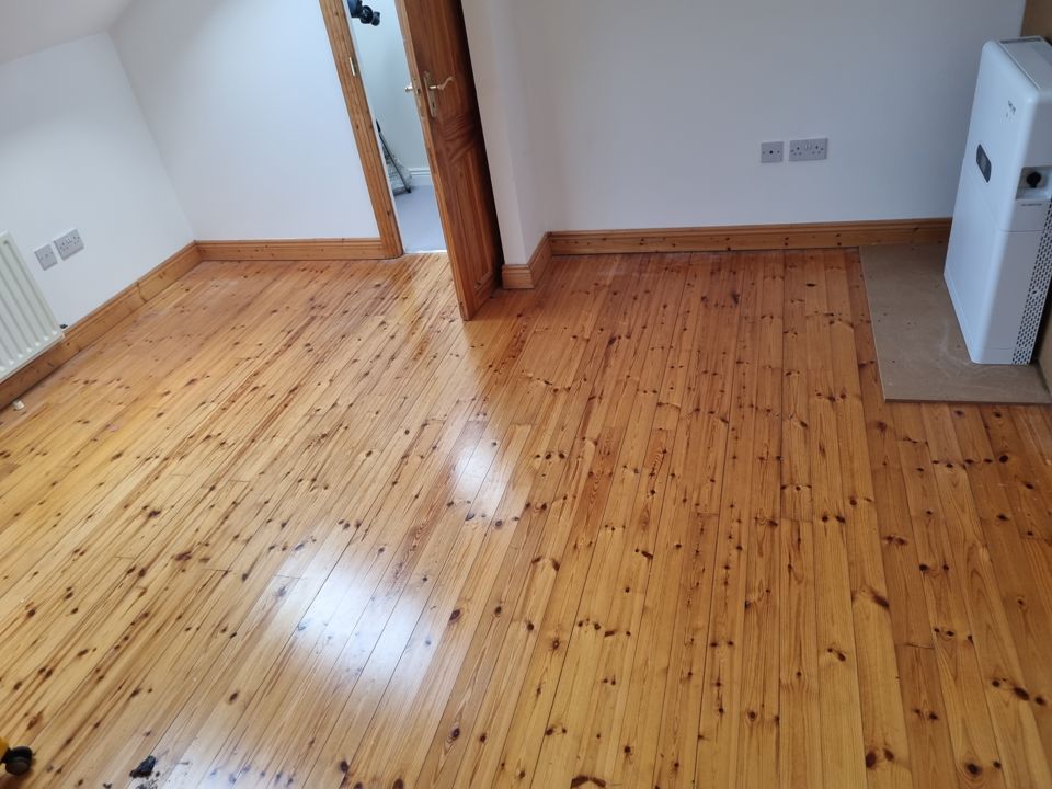The same loft room empty with polished floorboards after clearance