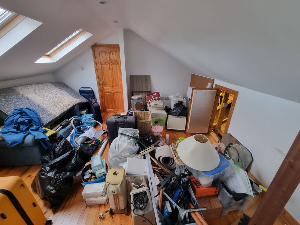 Loft bedroom full of bags, lamps and furniture before clearance