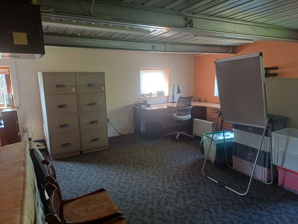 Home office with filing cabinets, desk, chair, flipchart and storage crates to be cleared