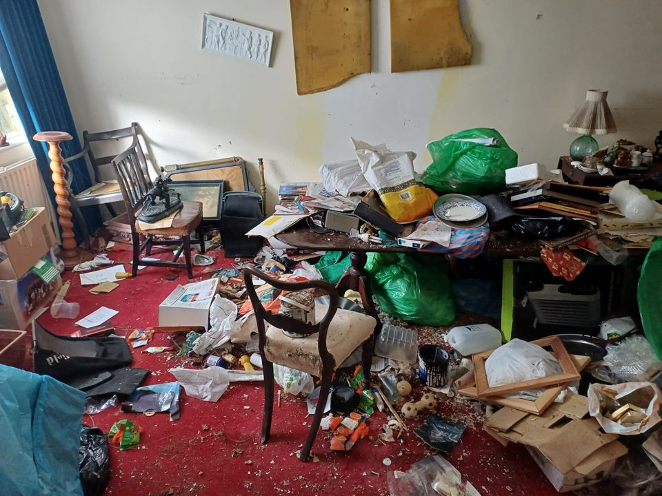 Furniture and rubbish piled in a room before clearance