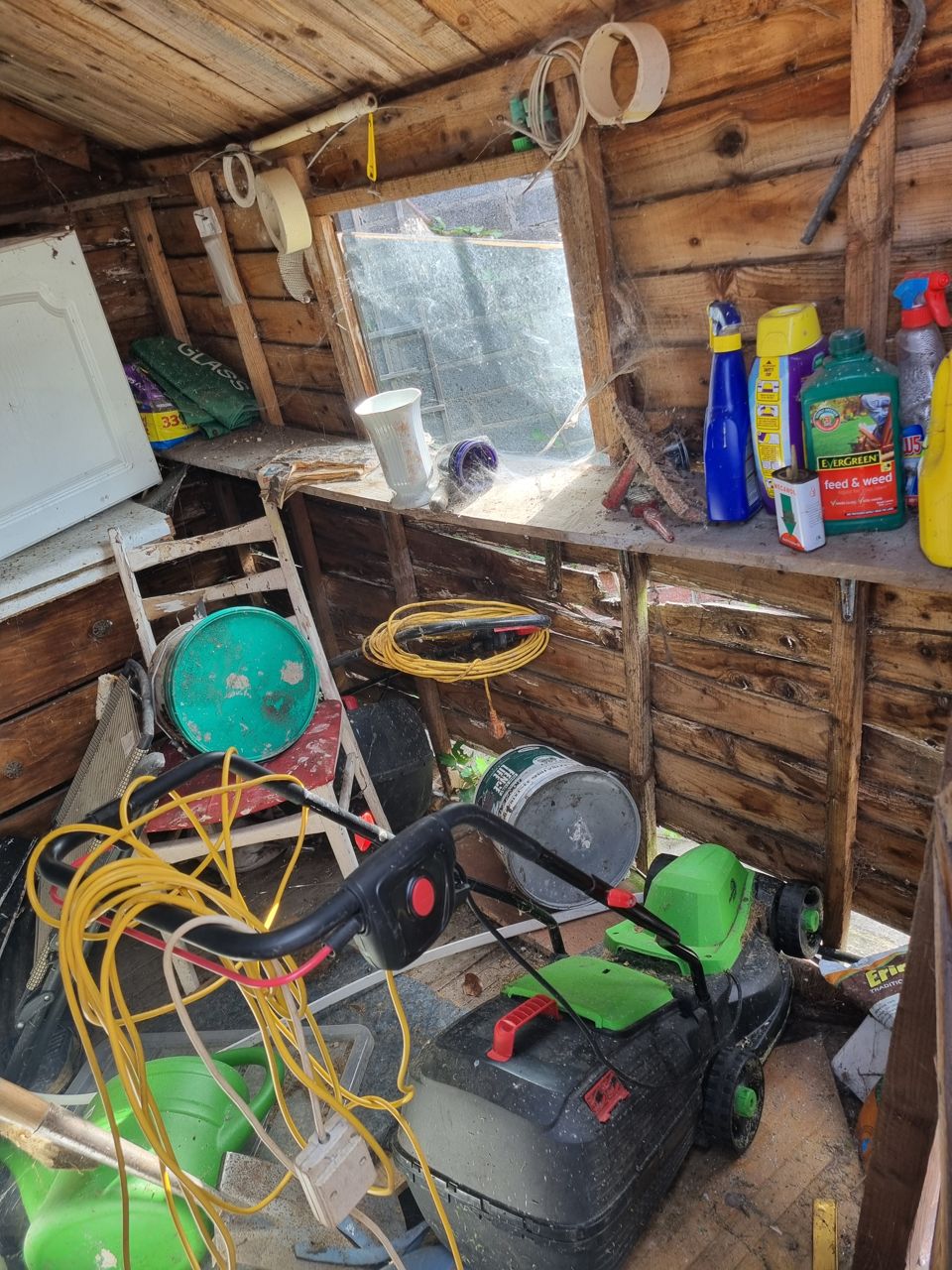 Inside a garden shed packed with hoses, tools and paint before clearance