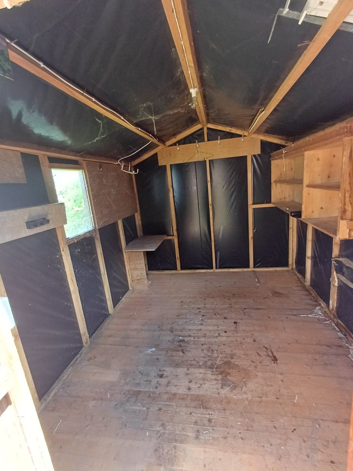 Garden shed interior completely emptied, bare wooden floor and empty shelving after shed clearance
