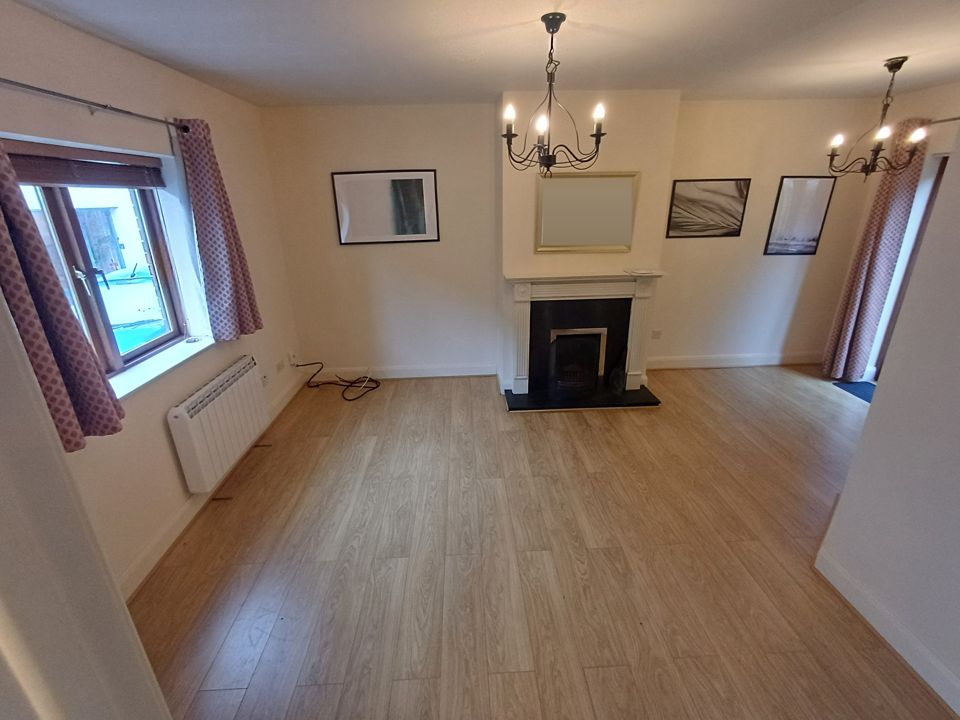 The same sitting room after the clearance, emptied and swept, fireplace and laminate floor showing