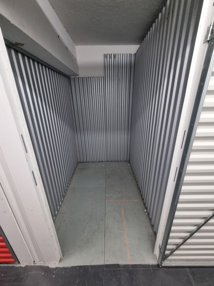 Empty corrugated-metal self-storage unit with door rolled up after the unit was cleared