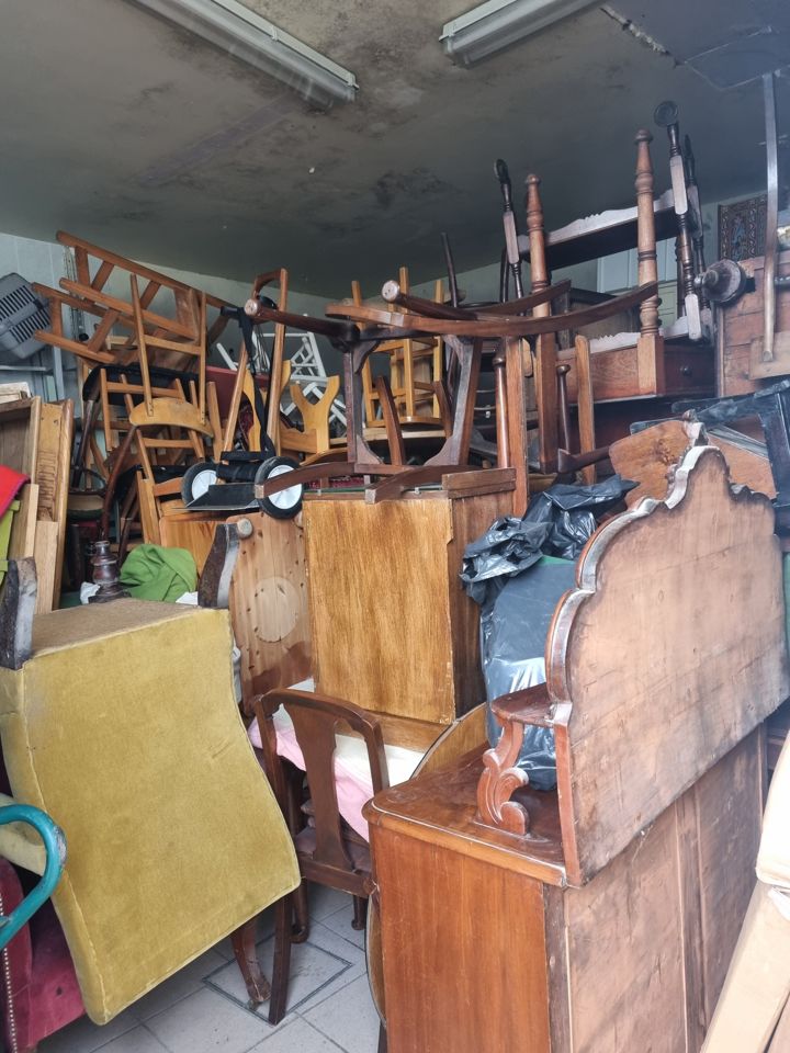 Storage room crammed floor to ceiling with stacked chairs, cabinets, headboards and furniture
