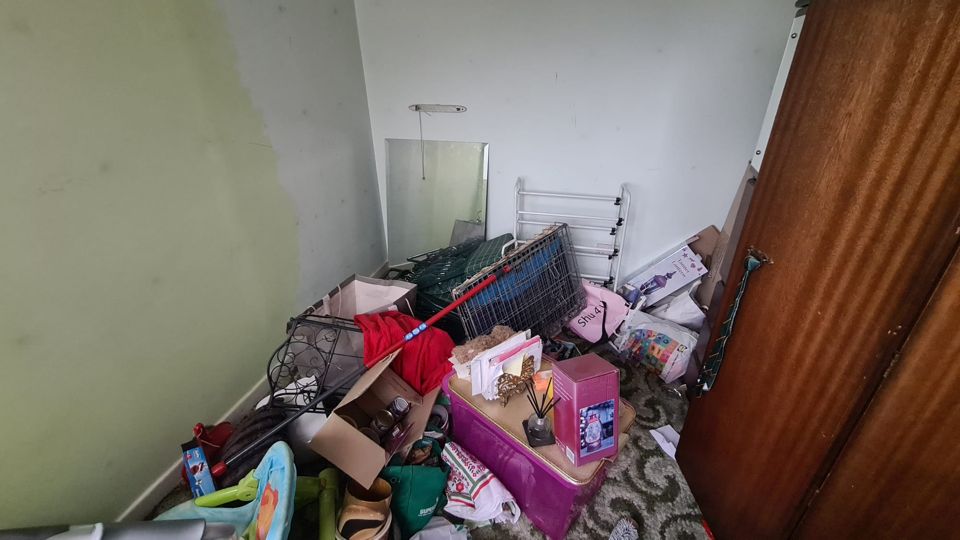 Green bedroom full of furniture and boxes before clearance, Sutton
