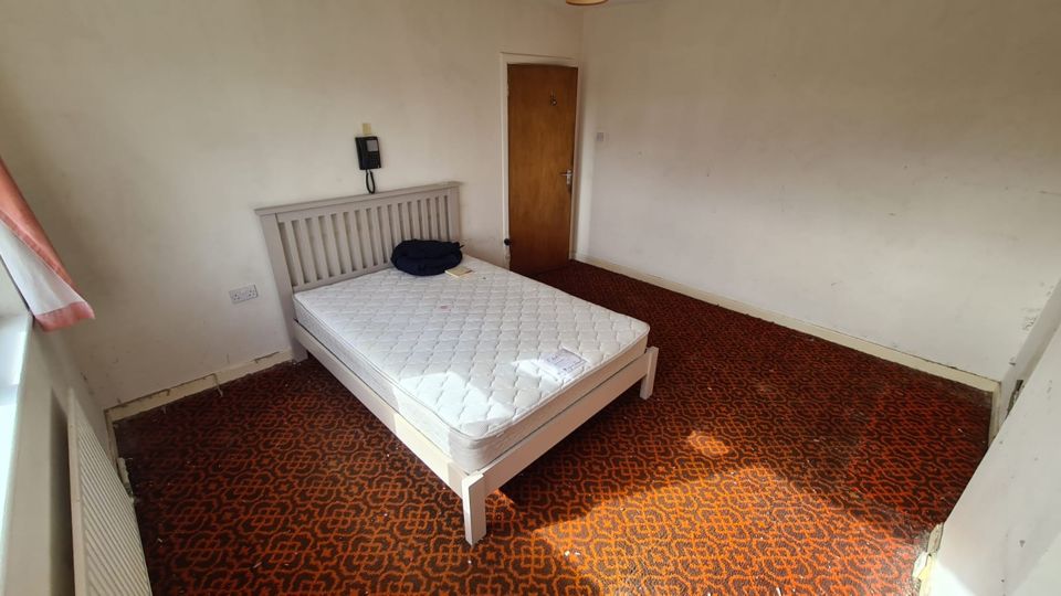 Bedroom with red patterned carpet after clearance, only the bed left, Sutton