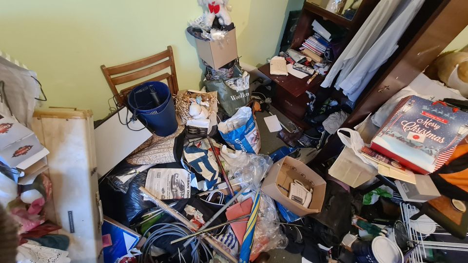 Room with a chair, boxes and clutter before clearance, Sutton