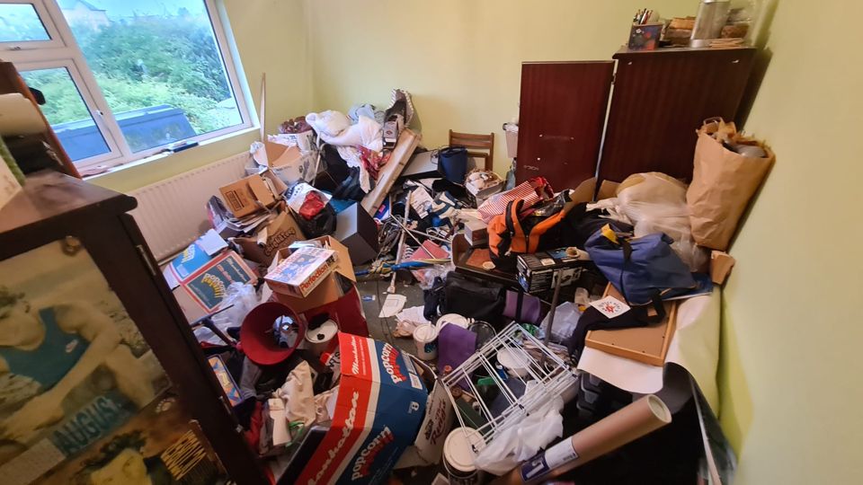 Bedroom with dark wardrobe and piled belongings before clearance, Sutton
