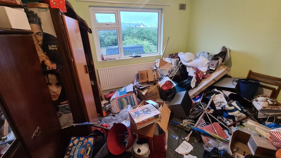 Yellow bedroom crammed with belongings before clearance, Sutton