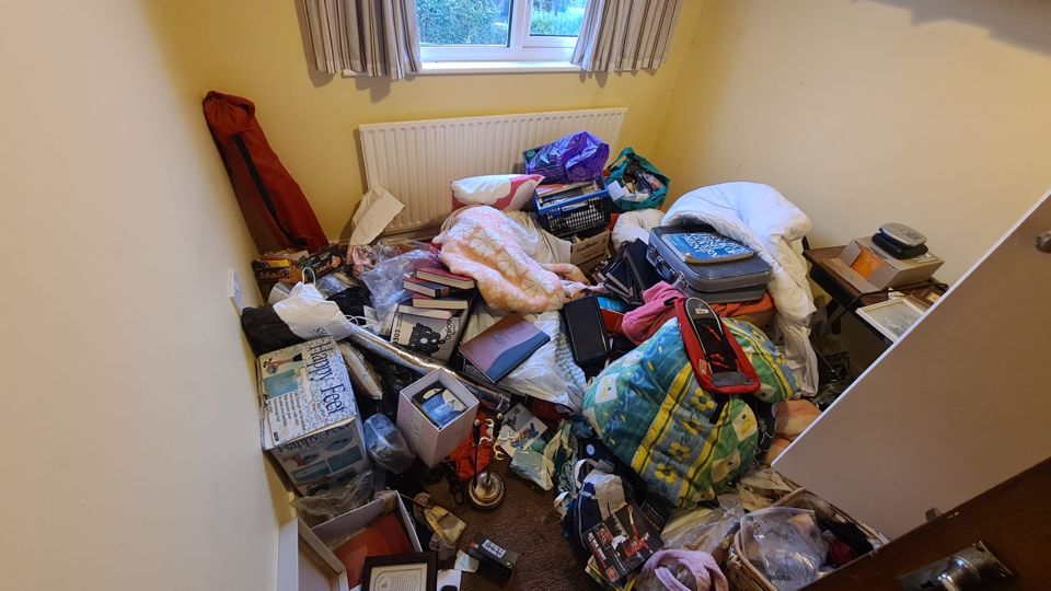 Yellow bedroom piled with belongings before clearance, Sutton