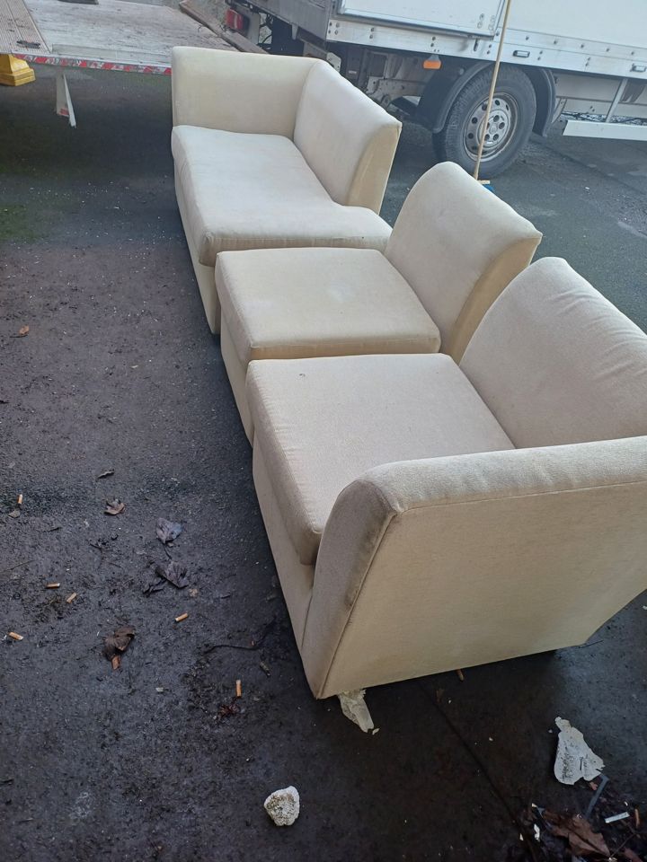 Sofa sections beside the box van with tail-lift lowered, mid-unload after a clearance job; no plate visible