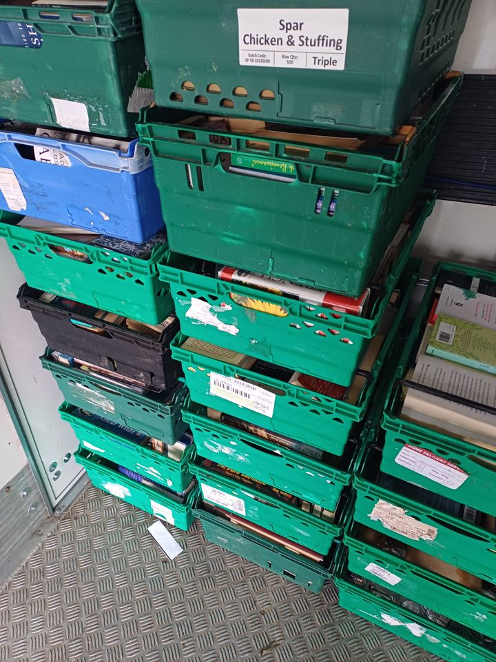 Stacks of green crates full of books loaded inside the box van on a chequer-plate floor