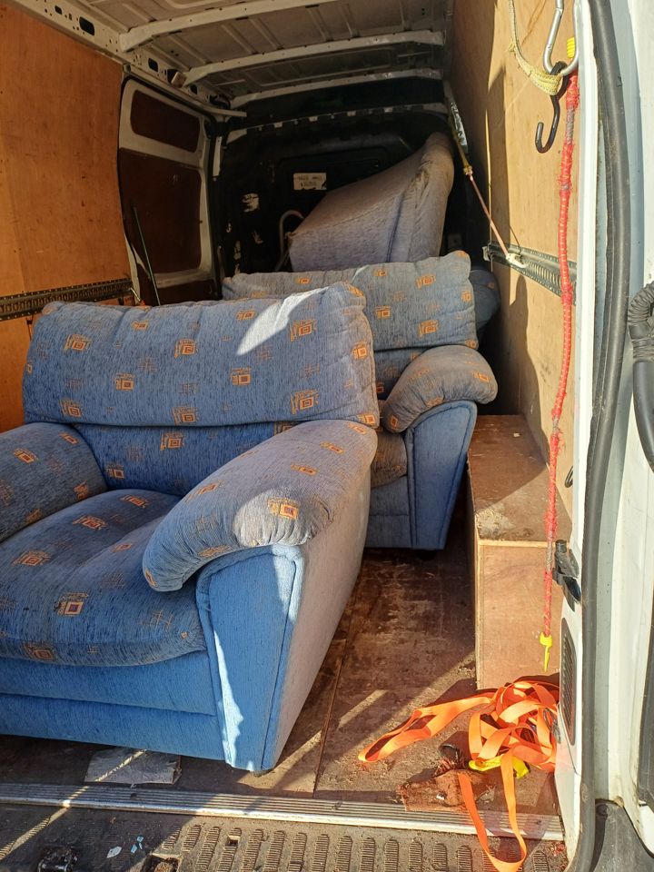 Two fabric armchairs strapped inside the van cargo area during a furniture collection