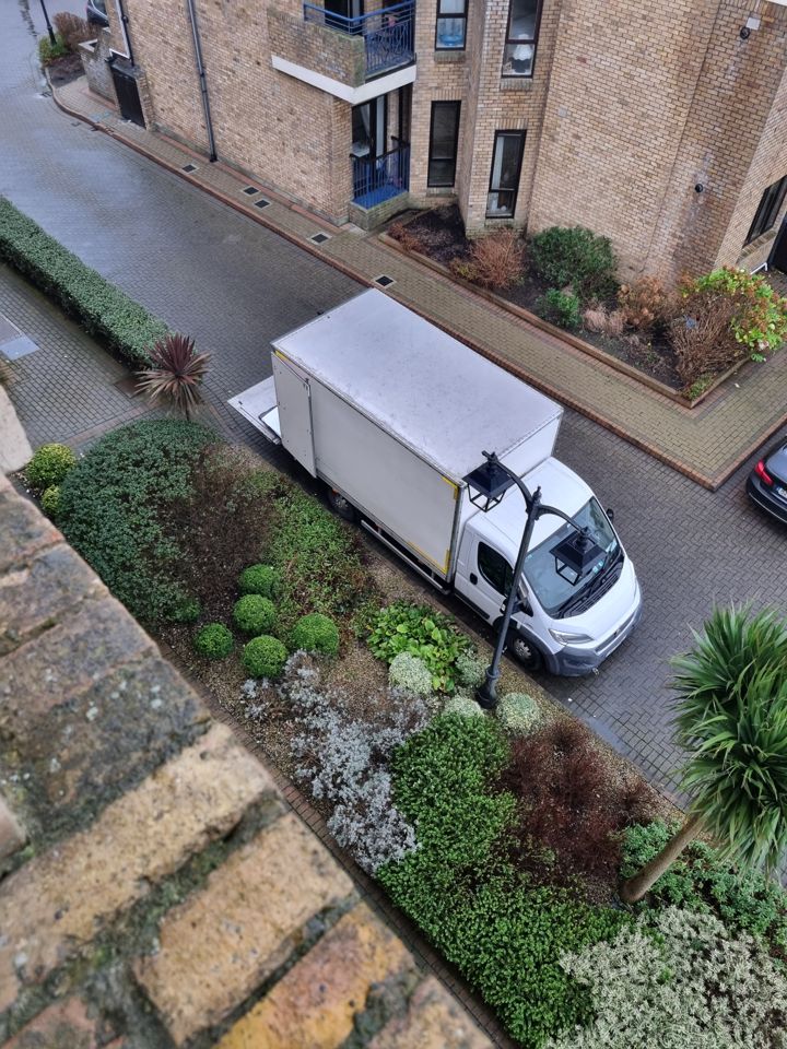 Company box van parked outside an apartment block, seen from above with tail lift ready